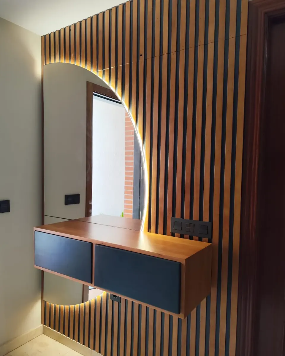 Recibidor con pared de listones de madera, espejo semicircular retroiluminado led y mueble colgado de dos cajones